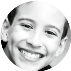 Fotografía circular en blanco y negro de un niño sonriendo ampliamente.
