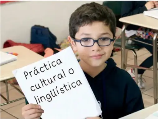 Niño sosteniendo un cartel que dice 'Práctica cultural o lingüística'.