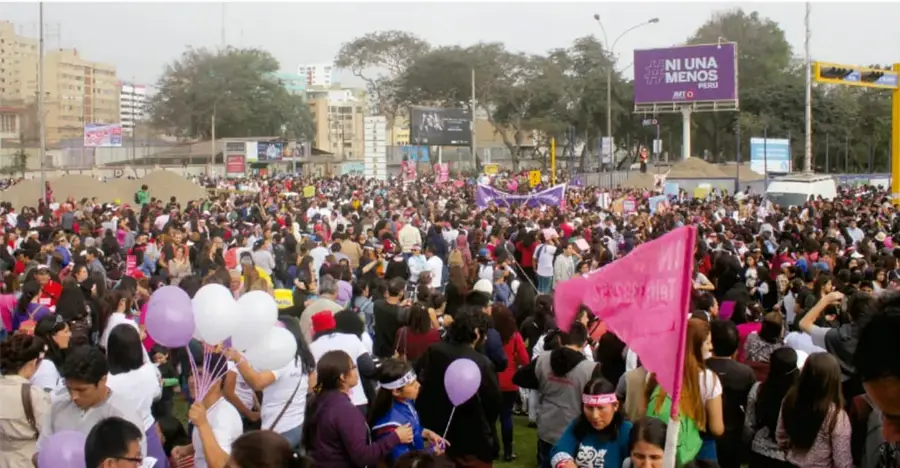Fotografía de una movilización multitudinaria en una ciudad mexicana, con globos morados y una pancarta que dice 'NI UNA MENOS PERÚ', símbolo de la lucha contra la violencia de género; representa la participación ciudadana en la defensa de los derechos humanos.