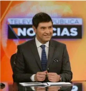Presentador de noticias en un set de televisión con el letrero 'TELECOMUNICACIONES NO CIAS'.