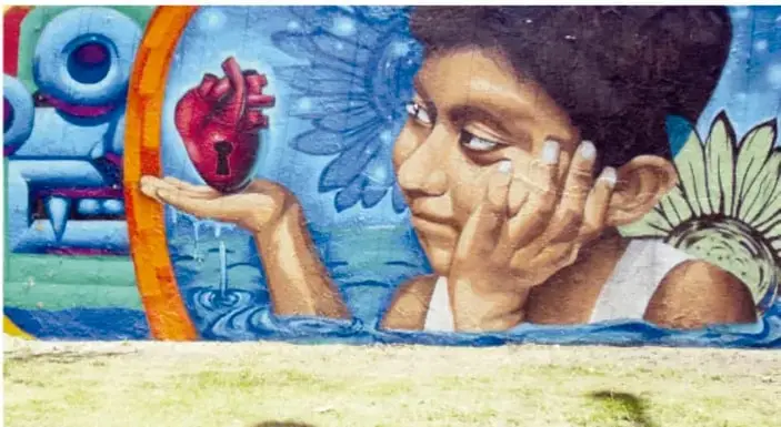 Mural de una niña que sostiene en la mano un corazón anatómico con una llave, entre motivos acuáticos y ornamentales.