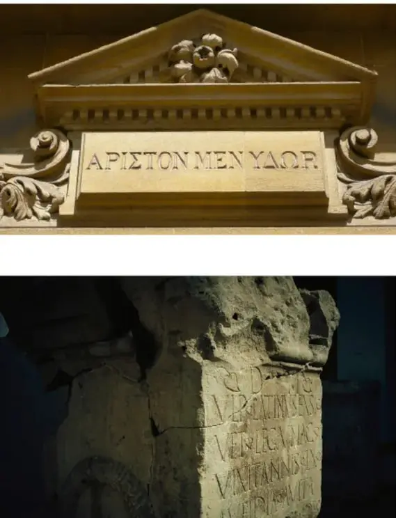 Fotografía de un frontón arquitectónico clásico con la inscripción griega "ΑΡΙΣΤΟΝ ΜΕΝ ΥΔΩΡ" ("lo mejor es el agua"), alusión a las raíces griegas del lenguaje.