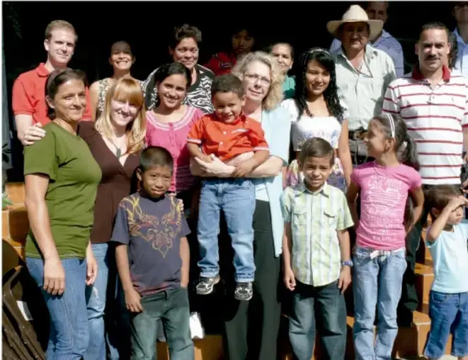 Fotografía de un grupo amplio de personas —adultos, niñas y niños de distintas edades— posando juntos al aire libre, probablemente integrantes de una comunidad que participó en el proyecto académico.