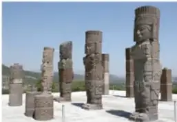 Atlantes de Tula: grandes figuras antropomorfas de piedra de pie en un sitio arqueológico con montañas al fondo.