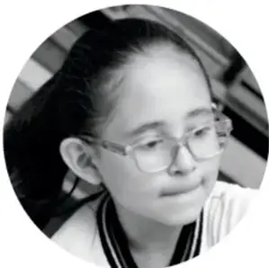 Fotografía de una niña con lentes que observa y participa en la actividad.