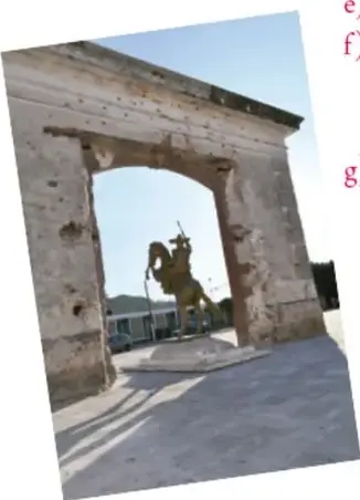 Arco de piedra con una escultura ecuestre al fondo, en un espacio público.