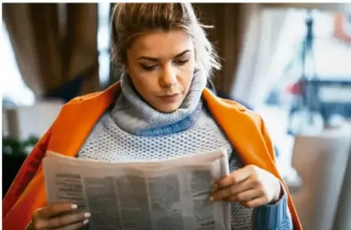Fotografía de una joven leyendo un periódico impreso, ilustrando la lectura de textos periodísticos.