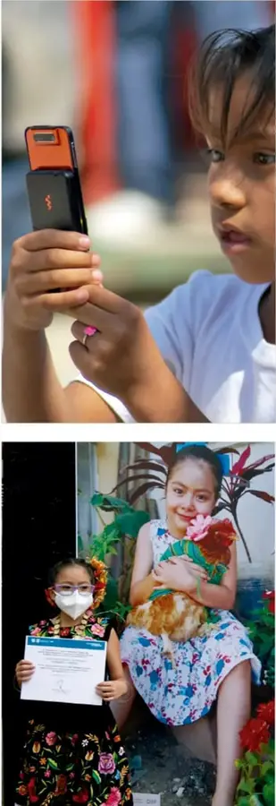 Primer plano de una niña que sostiene y mira un teléfono celular con funda naranja y negra.