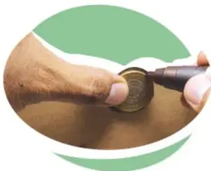 Mano marcando con plumón el contorno de una moneda de 10 pesos en la caja.