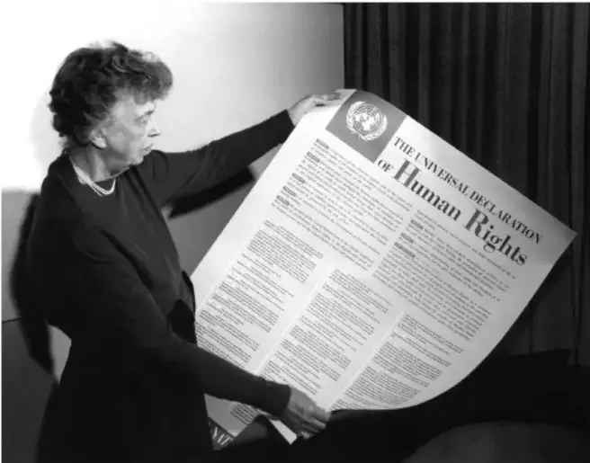 Fotografía en blanco y negro de una mujer sosteniendo un cartel con la Declaración Universal de los Derechos Humanos de la ONU.