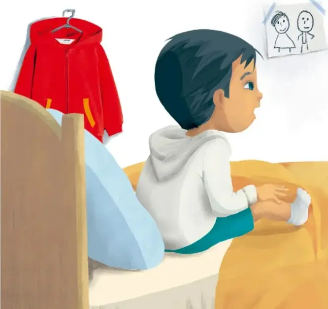 Julián sentado en su cama, mirando hacia la puerta; junto a él hay un dinosaurio de juguete verde y un dibujo pegado en la pared.