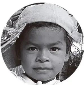 Fotografía en blanco y negro de un niño con sombrero, de mirada seria, que representa a Juan o a un estudiante de la comunidad.