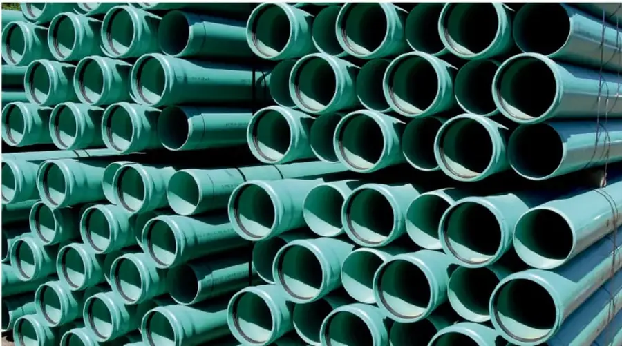Fotografía de un gran número de tuberías de plástico verde apiladas, ilustrando el uso del plástico en tuberías en sustitución de los metales.