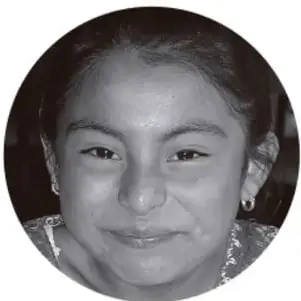 Fotografía en blanco y negro de una niña de primaria sonriendo, en formato circular.