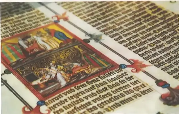 Fotografía de un manuscrito medieval con texto, decoraciones e imágenes iluminadas.
