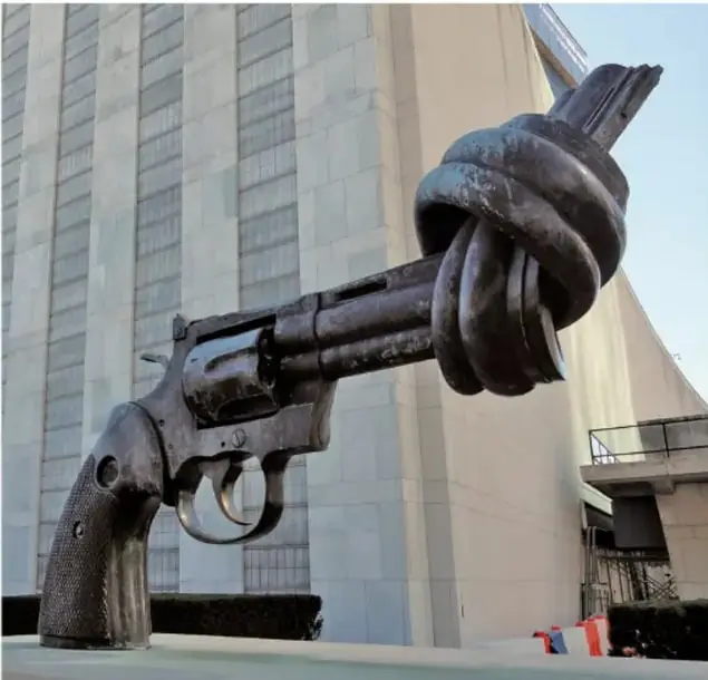 Escultura de un revólver con el cañón atado en un nudo (obra 'Knotted Gun' de Carl Fredrik Reuterswärd), símbolo internacional de la cultura de paz y el rechazo a la violencia, ubicada frente a un edificio institucional.