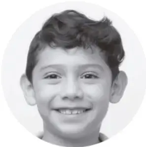 Fotografía en blanco y negro de un niño sonriente, con el cabello oscuro y crespo, mirando a la cámara.