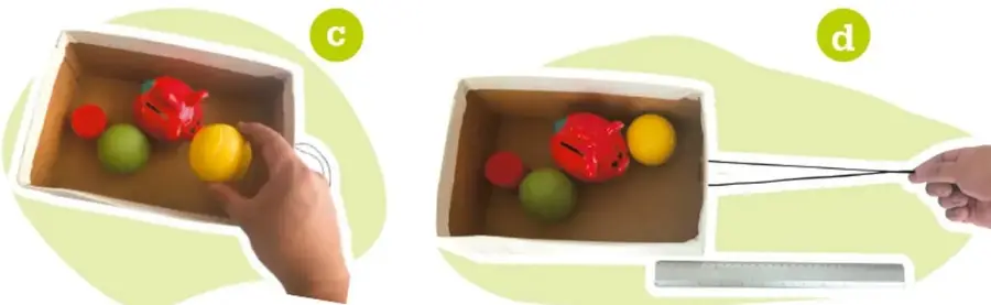 Mano colocando objetos (pelotas rojas, verdes y amarillas) dentro de una caja de cartón.