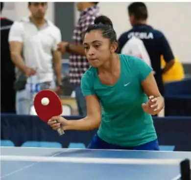 Jugadora de tenis de mesa en pleno partido, con raqueta y pelota, ilustrando el deporte educativo.