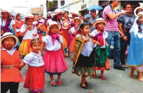 Niñas y niños participan en una celebración tradicional con vestimenta colorida, relacionada con el catolicismo popular y el Pase del Niño.