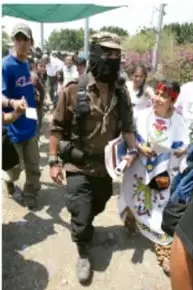 Personas caminando, una de ellas con pasamontañas, en un contexto de marcha o protesta.