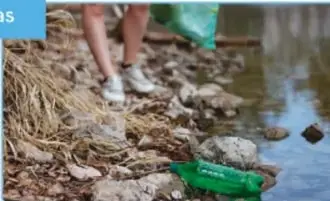 Persona caminando entre residuos sólidos en la orilla de un río o playa.