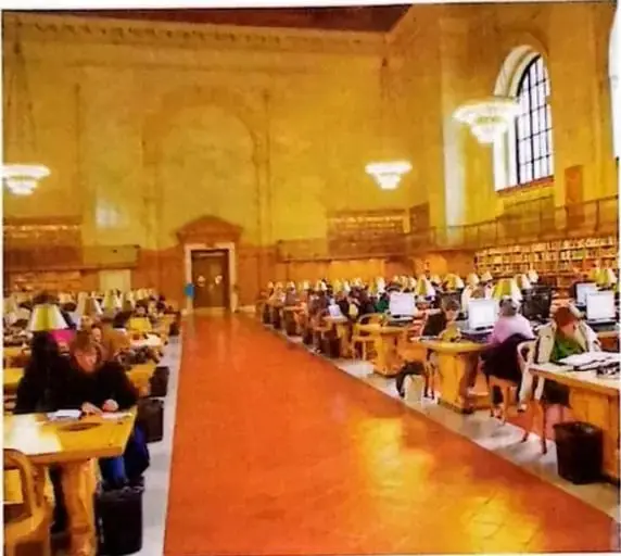 Fotografía de una biblioteca con personas leyendo o investigando.