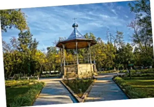 Quiosco con cúpula en un jardín con caminos y árboles.