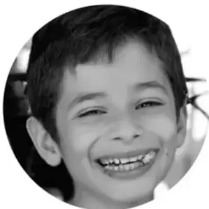 Fotografía en blanco y negro de un niño sonriente de primaria.