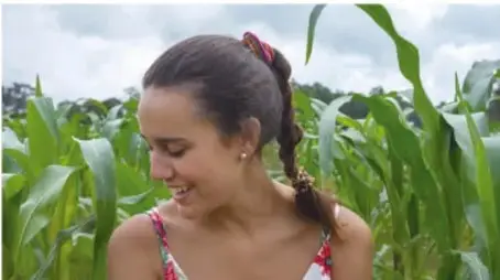 Mujer joven sonriendo en un campo de cultivo.