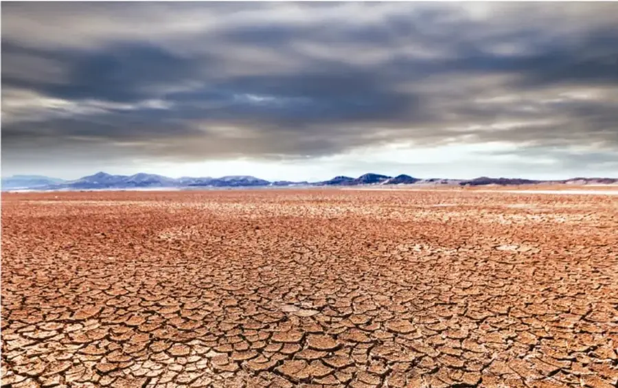 Fotografía de un suelo agrietado y seco que se extiende hasta el horizonte bajo un cielo nublado, representando la degradación y desertificación de la tierra agrícola.