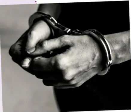 Fotografía en blanco y negro de manos esposadas, simbolizando la detención injusta.