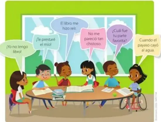 Escena con seis niños alrededor de una mesa con libros, conversando; uno de ellos usa silla de ruedas.