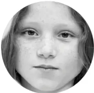 Retrato en blanco y negro de una niña con pecas mirando de frente.