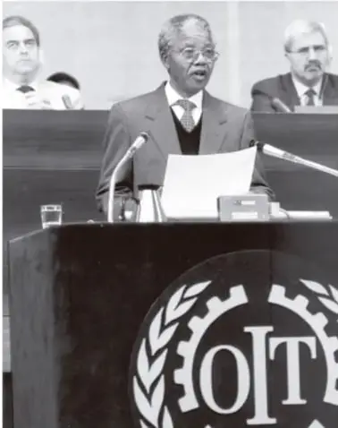 Nelson Mandela hablando en un atril con el emblema de la OIT al frente.