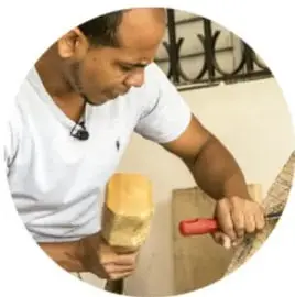 Persona trabajando una pieza con herramienta, rótulo 'Escultura'