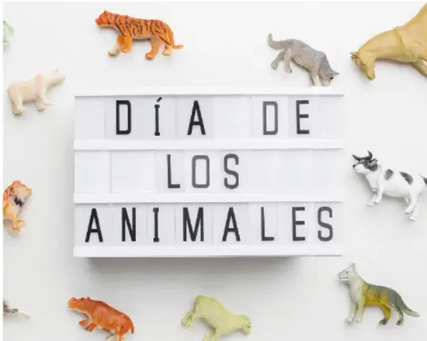 Cartel iluminado con la leyenda 'DÍA DE LOS ANIMALES' rodeado de figuras de animales (tigre, oso, lobo, vaca, rana, león, caballo, etc.) sobre fondo blanco.
