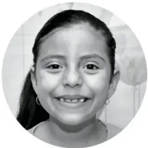 Fotografía en círculo de una niña sonriente con trenzas, presumiblemente Karla.