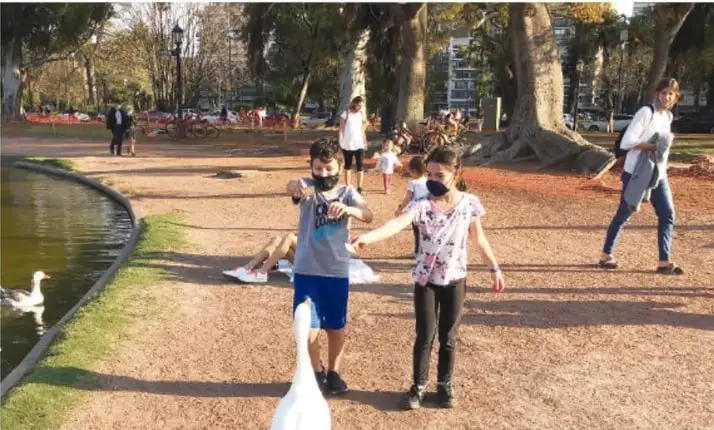 Fotografía de un parque con árboles, un lago y varias personas caminando, como ejemplo de descripción de lugares.