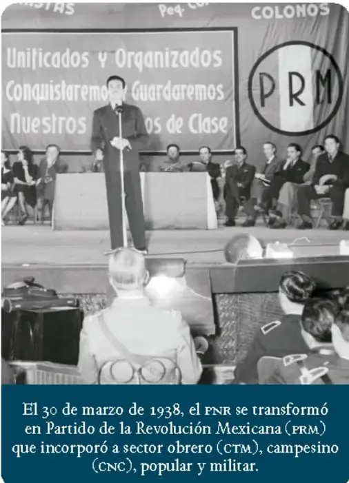 Fotografía en blanco y negro de una reunión política. Un hombre habla en un micrófono frente a un grupo de personas sentadas. Detrás hay una manta con las palabras 'Unificados y Organizados', 'Conquistaremos y Guardaremos', 'Nuestros ... de Clase' y el logotipo del PRM.