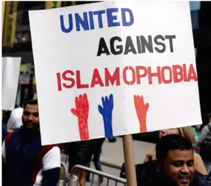 Fotografía de una protesta con un cartel que dice 'UNITED AGAINST ISLAMOPHOBIA' con manos de colores rojo, azul y rojo.