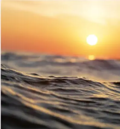 Fotografía de un atardecer o amanecer sobre el mar con el Sol cercano al horizonte.