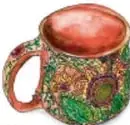 Taza de barro decorada con motivos florales de colores verde, rojo y amarillo.