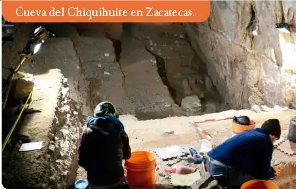 Fotografía de una piedra tallada (posible punta Clovis) sostenida por una mano.