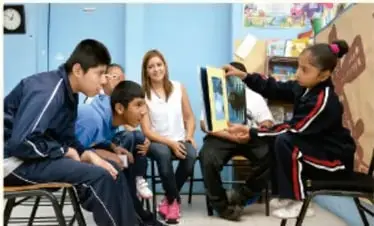Grupo de estudiantes y adultos en una actividad grupal, posiblemente en un aula o taller.
