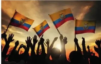 Personas ecuatorianas sostienen banderas del Ecuador al atardecer. La imagen representa el orgullo y la defensa de la soberanía nacional.