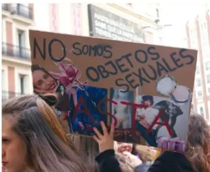 Persona sostiene un cartel en una marcha con la frase 'NO SOMOS OBJETOS SEXUALES', acompañada de otras personas.