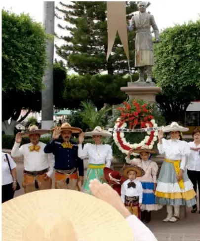 Personas con vestimenta tradicional reunidas alrededor de un monumento.