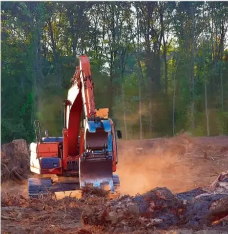 Fotografía de una excavadora trabajando en un terreno deforestado, simbolizando la explotación de recursos y el impacto ambiental en zonas de conflicto.