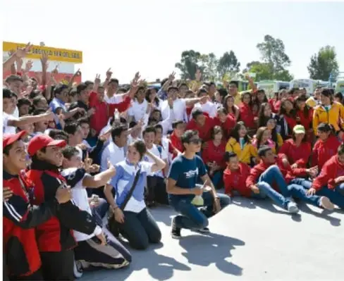 Fotografía de un gran grupo de estudiantes de secundaria reunidos al aire libre, muchos levantando las manos; leyenda: Gimenna Schiafini Rosales, PUEBLA.